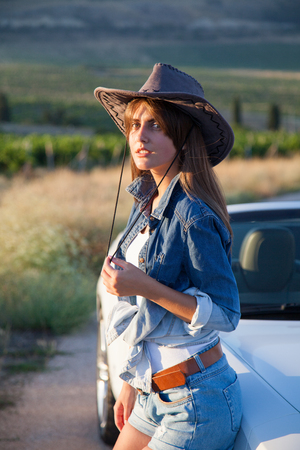 beautiful woman cowboy stands at White convertibleの写真素材