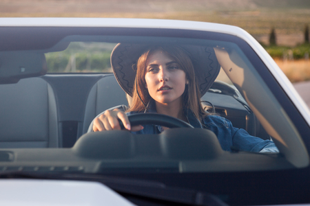 Cowboy girl driver sits in white cabrioletの写真素材