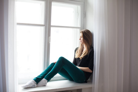 beautiful girl sitting at home in front of a window