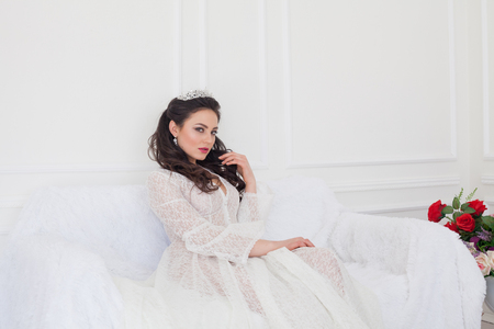bride in wedding dress sitting on a white couchの写真素材