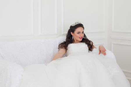 bride in wedding dress sitting on the couchの写真素材