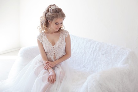 beautiful girl in lingerie sitting on a white couch weddingの写真素材