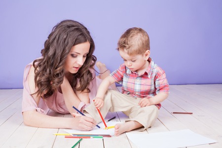 mother and young son play paint crayonsの写真素材
