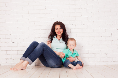 mom and young boy son sit on the floor brick wallの写真素材