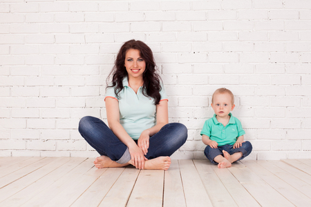 mom and young boy son sit on the floor brick wallの写真素材