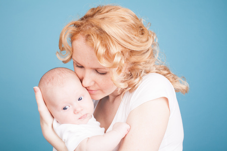 mom looks lovingly at baby son keeps on handの写真素材