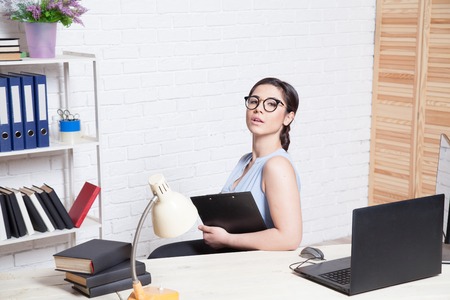 business girl sits at a computer in the Office paper foldersの写真素材