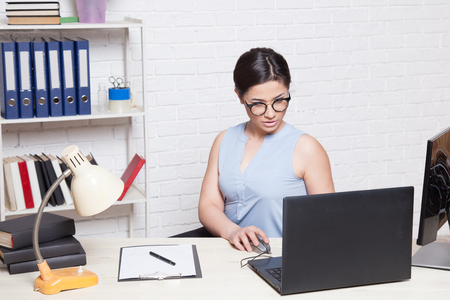 business girl sits in an Office behind a desk with a computerの写真素材