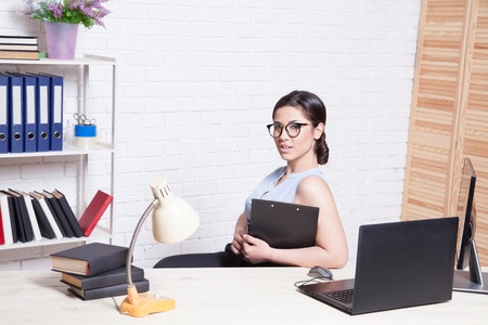 business girl sits at a computer in the Office paper foldersの写真素材