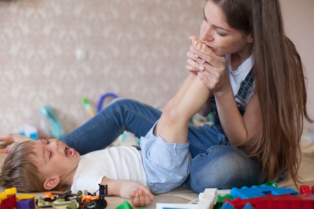 mom plays with a little boy with love kisses laughsの写真素材