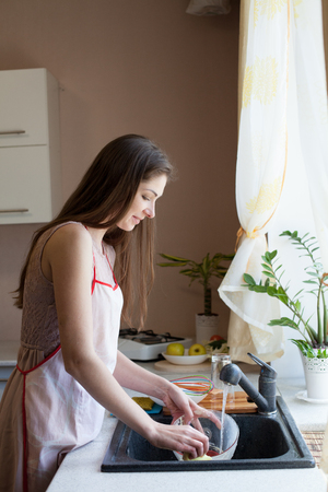 girl housewife washes dirty dishes in the kitchenの写真素材