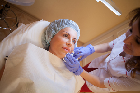 doctor beautician increases lip patient an injection syringeの写真素材