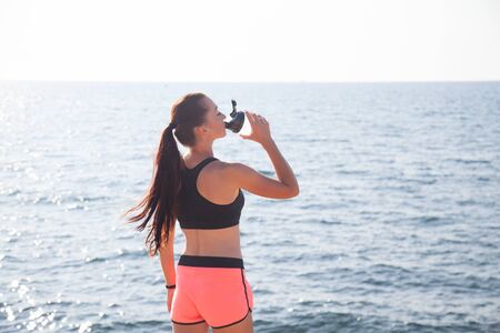 girl drinking water from a blender after sportsの写真素材