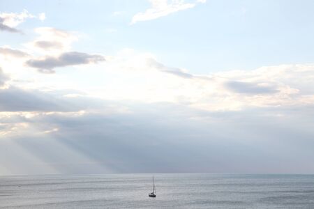 yacht in the sea rays from clouds landscapeの写真素材
