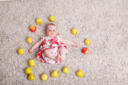 baby girl lying on the floor with Green applesの写真素材