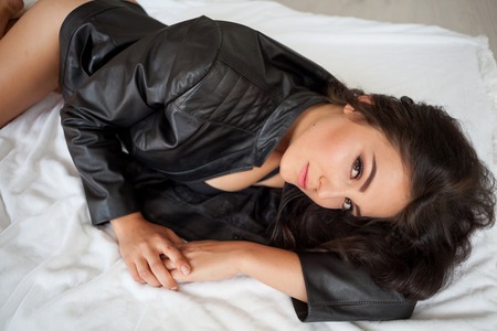 girl in black lingerie is lying on a white bedの写真素材