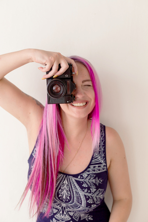 photographer girl with pink hair on a photo shoot with a cameraの写真素材