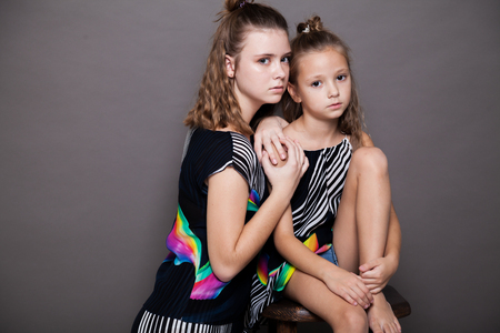 two girls fashionable posing on a grey backgroundの写真素材