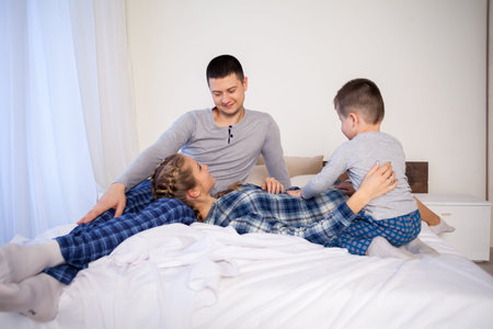 mom dad son in the morning in bedの写真素材