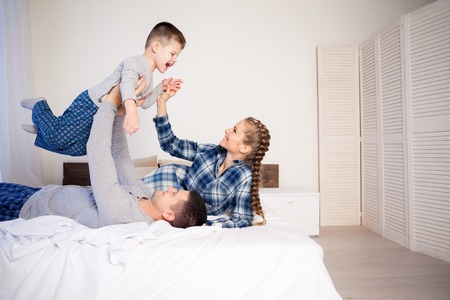 mom dad son in the morning in bedの写真素材