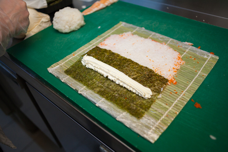 woman in white chef prepares sushi restaurantの写真素材