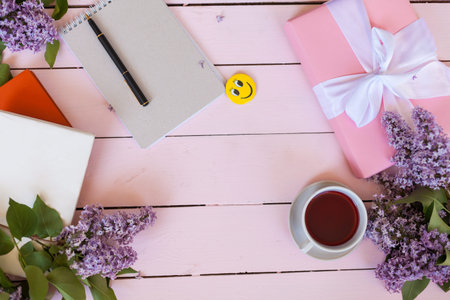 on the white table lilac, gift, notebook, cup of tea