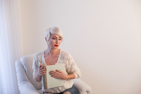woman reading a book prepared for the exam in a white roomの写真素材