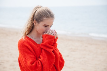 woman drinking hot coffee or tea on the sandy beachの写真素材