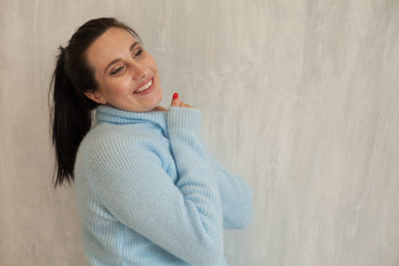 Portrait of beautiful pregnant woman in the blue jacket on a grey background