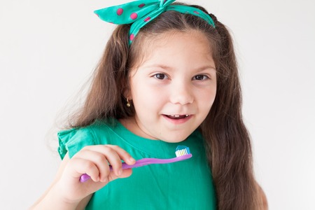 little girl with no teeth with a toothbrush in dentistryの写真素材