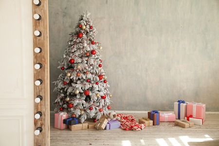 Christmas snowy Christmas tree with presents in a white room in winterの写真素材