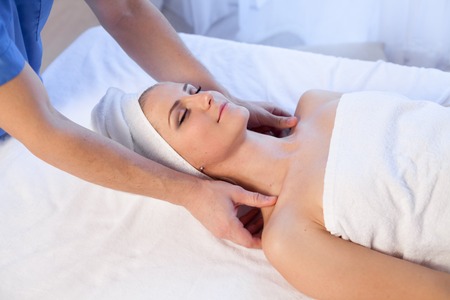 a massage therapist makes a beautiful woman face and body medical massage in the Spaの写真素材