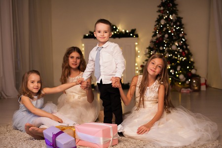 the little boy and three girls kids open Christmas presents new year winter Christmas treeの写真素材