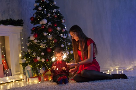 mother and young son sparklers gifts new year Christmas treeの写真素材