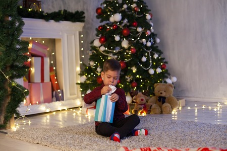 little boy opens Christmas gifts at the Christmas new yearの写真素材