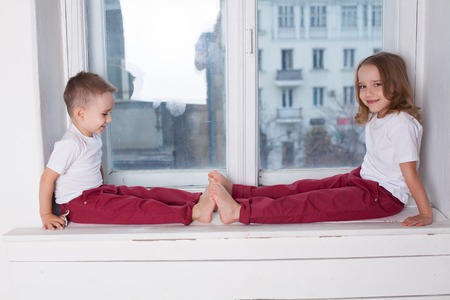 the little boy and girl alone at home watching in the windowの写真素材