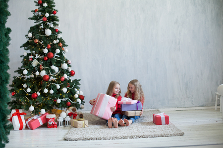 two girls opens Christmas presents new year Christmas tree Garland lightsの写真素材