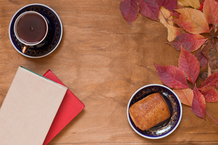 Cup of tea with pastry cake on wooden background with booksの写真素材