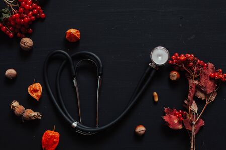 stethoscope on the table with autumn leaves and fruitの写真素材