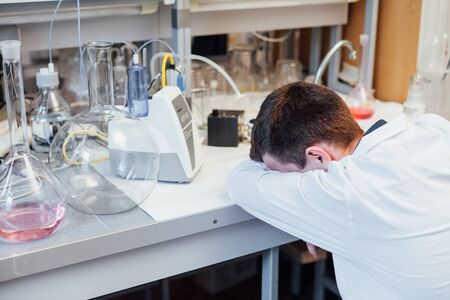 Male scientist tired of wanting to sleep after chemical experiments in labの写真素材