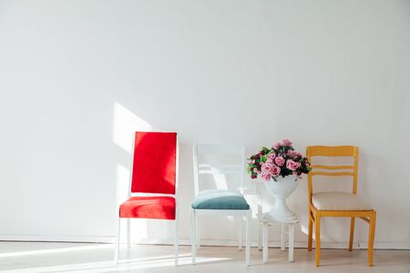 four multicolored chairs and a basket of flowers on a white backgroundの写真素材