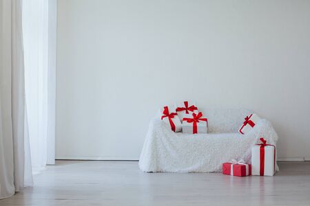 sofa in the interior of a white room with red gifts for a holidayの写真素材