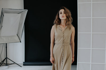 Portrait of a fashionable woman in a beige dress in a photo studio