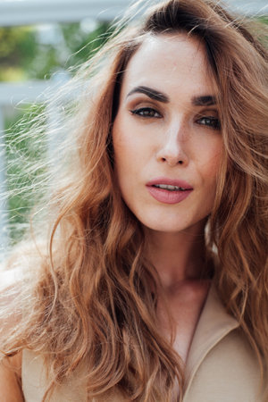 Portrait of a beautiful fashionable woman in a beige dress on a walk