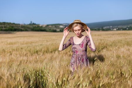 Beautiful fashionable woman blonde in a dress in a wheat fieldの写真素材