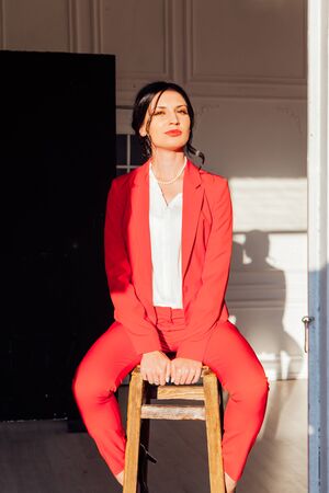Portrait of a brunette woman in a red business suit in the officeの写真素材