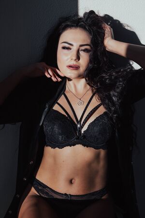Portrait of a beautiful fashionable woman in black underwear in the bedroomの写真素材