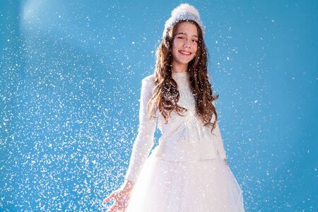 Beautiful fashionable girl in winter snow cap blue backgroundの写真素材