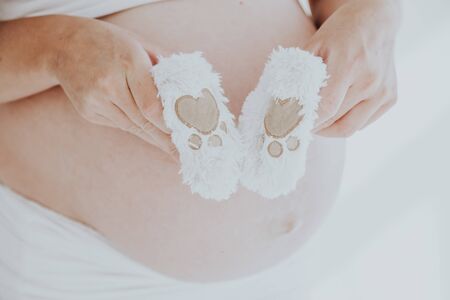 the stomach of a pregnant woman and baby stuff socksの写真素材