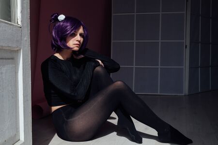 Beautiful woman anime cosplayer with purple hair in black fashion clothesの写真素材